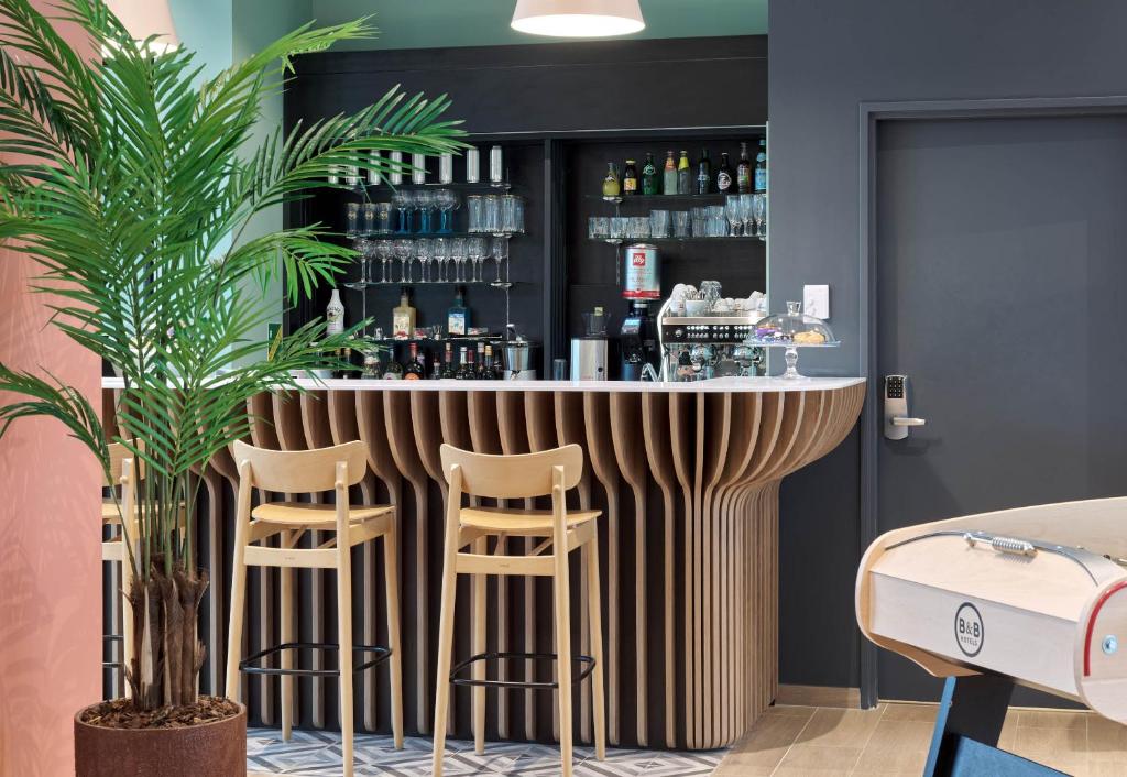 a bar in a room with two stools at B&B HOTEL Versailles Rocquencourt in Rocquencourt