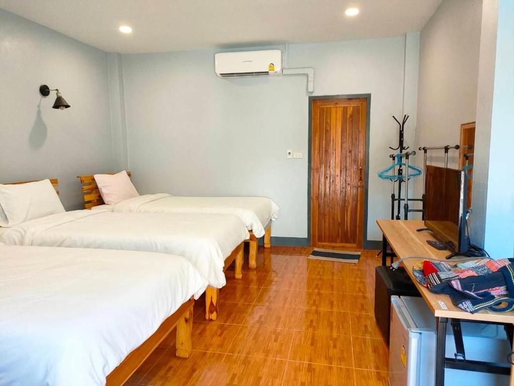 um quarto com três camas e uma televisão em เรือนวรา - Wara Guesthouse em Nan