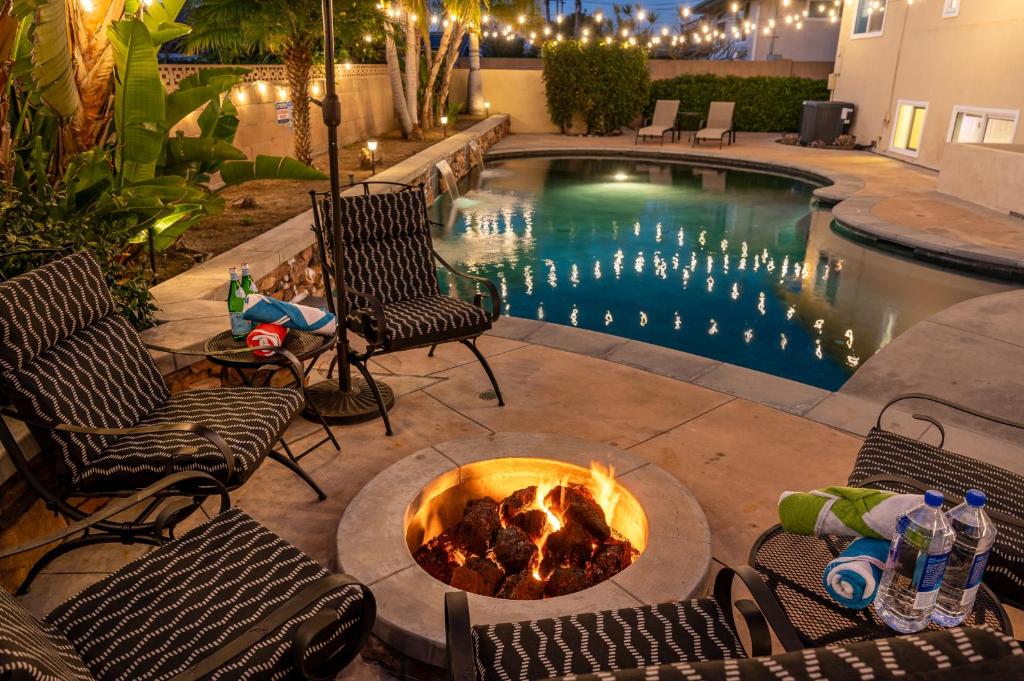 a pool with chairs and a fire pit next to a swimming pool at Amazing Modern Pool House near Disneyland in Anaheim