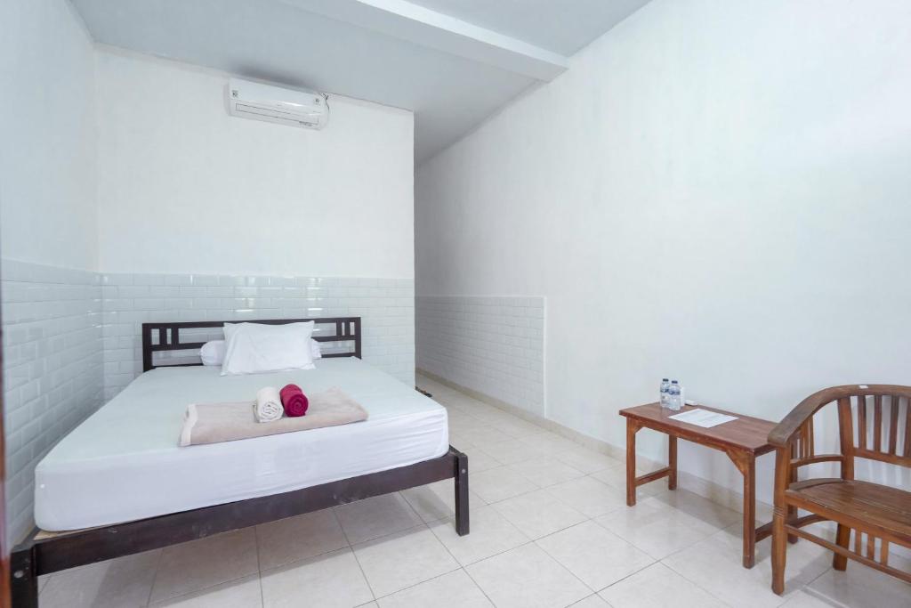 a bedroom with a bed and a table and a chair at SDK Homestay Uluwatu in Uluwatu