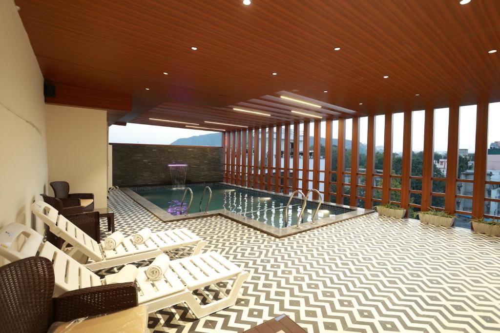 Großes Zimmer mit Pool und Balkon mit Stühlen in der Unterkunft Hotel Taviral Regency in Udaipur