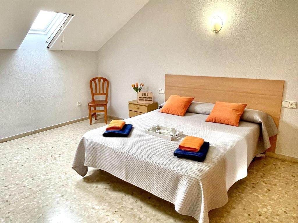 1 dormitorio con 1 cama grande con almohadas de color naranja en APARTBEACH EL PINAR CON PISCINA y BARBACOA en Reus