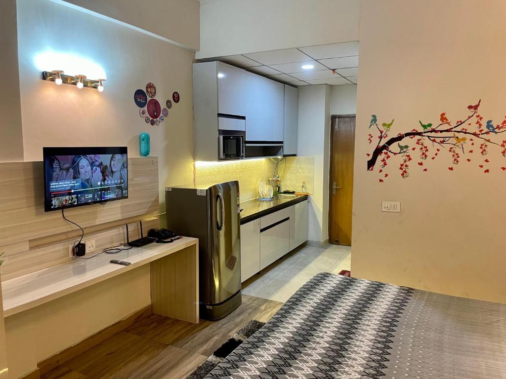 a kitchen with a refrigerator and a tv on a wall at Serene Stay India in Greater Noida