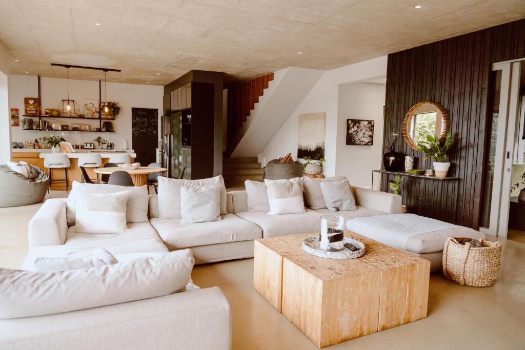 a living room with white couches and a table at Maison De Plage in Umdloti