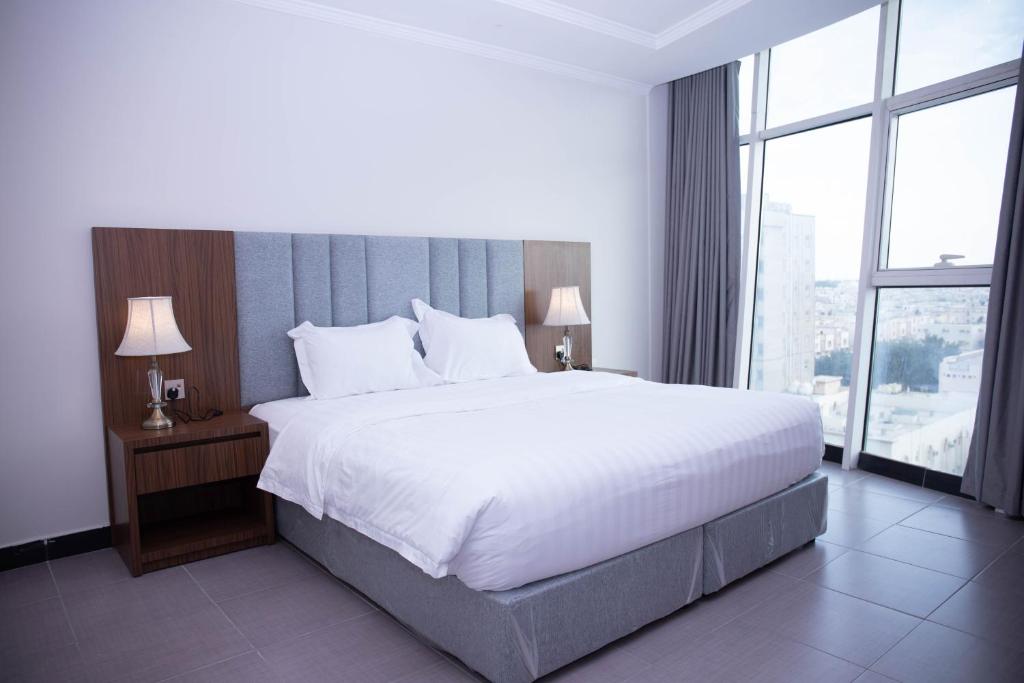 a bedroom with a large bed and a large window at Golden Suites in Al Jubail