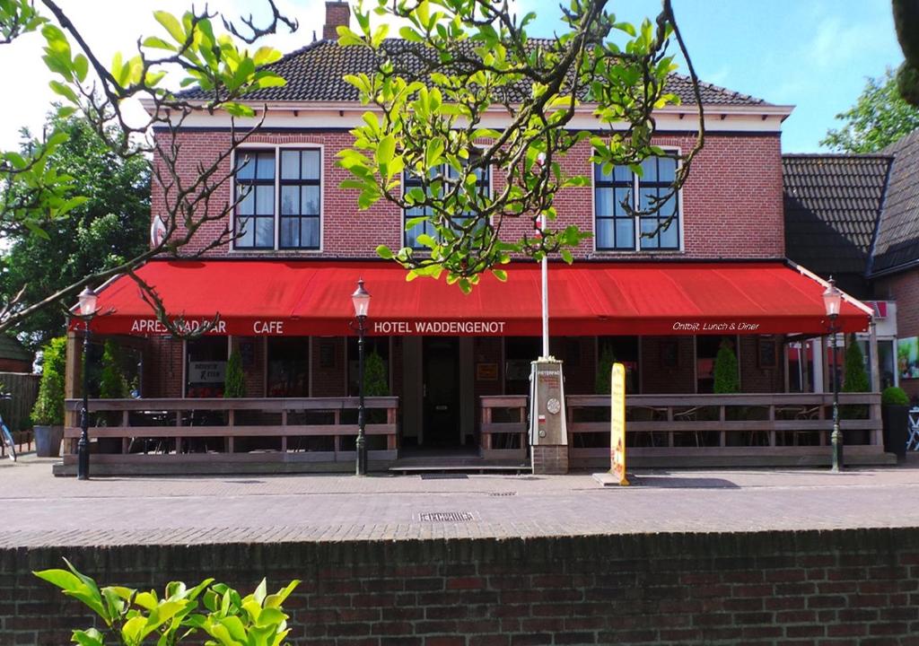 un bâtiment avec un auvent rouge dans une rue dans l'établissement Hotel Waddengenot, à Pieterburen