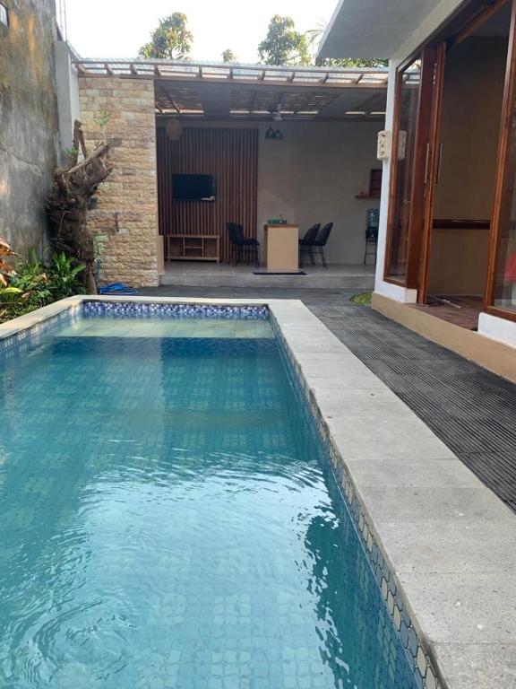 a swimming pool with blue water in front of a house at Pranajayaloka private villa in Tejakula