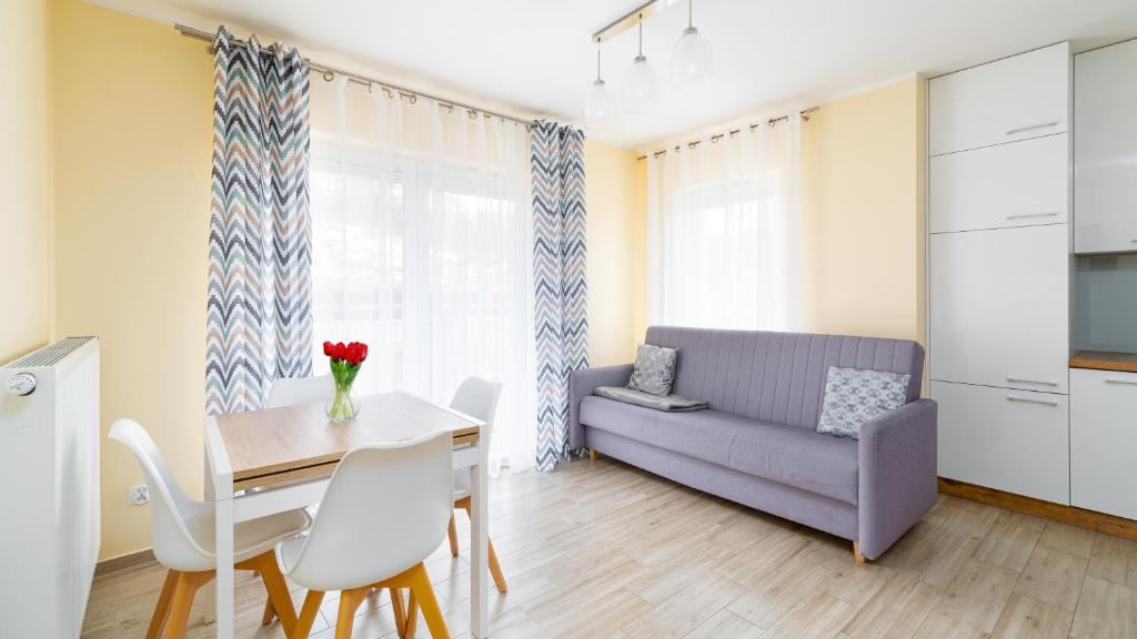 een woonkamer met een tafel en een paarse bank bij Apartamenty Sun & Snow Waryńskiego in Szklarska Poręba
