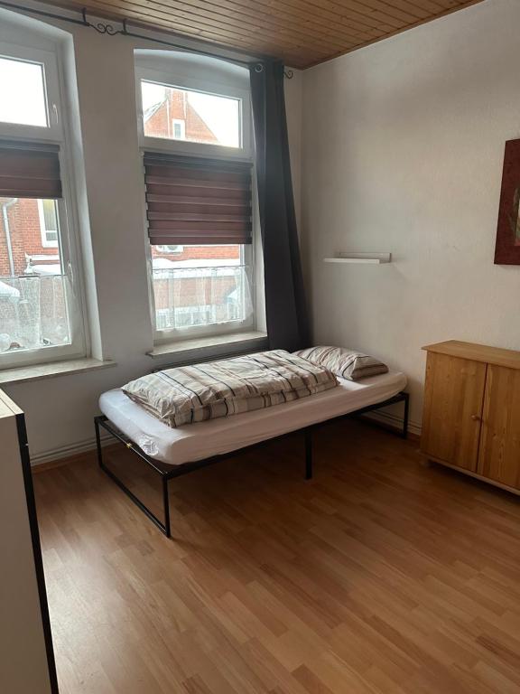 Bett in einem Zimmer mit 2 Fenstern in der Unterkunft Ferien Wohnung Elmaci in Itzehoe