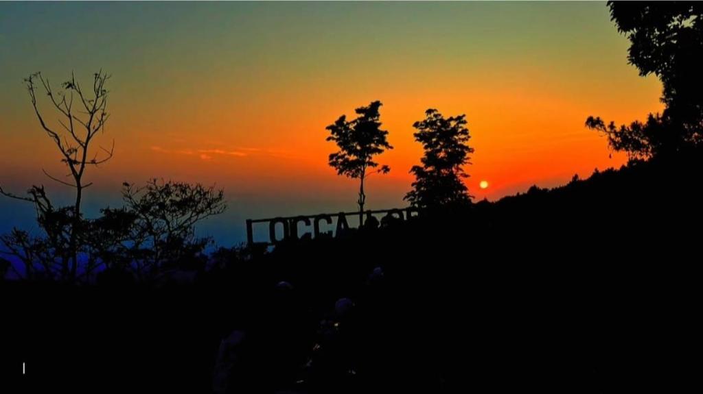 a sunset on top of a hill with trees at Locca Lodge in Mojokerto