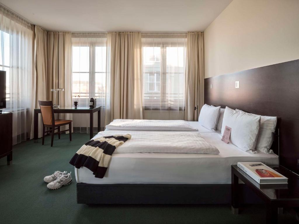 a hotel room with a large bed and a desk at Flemings Hotel München-City in Munich