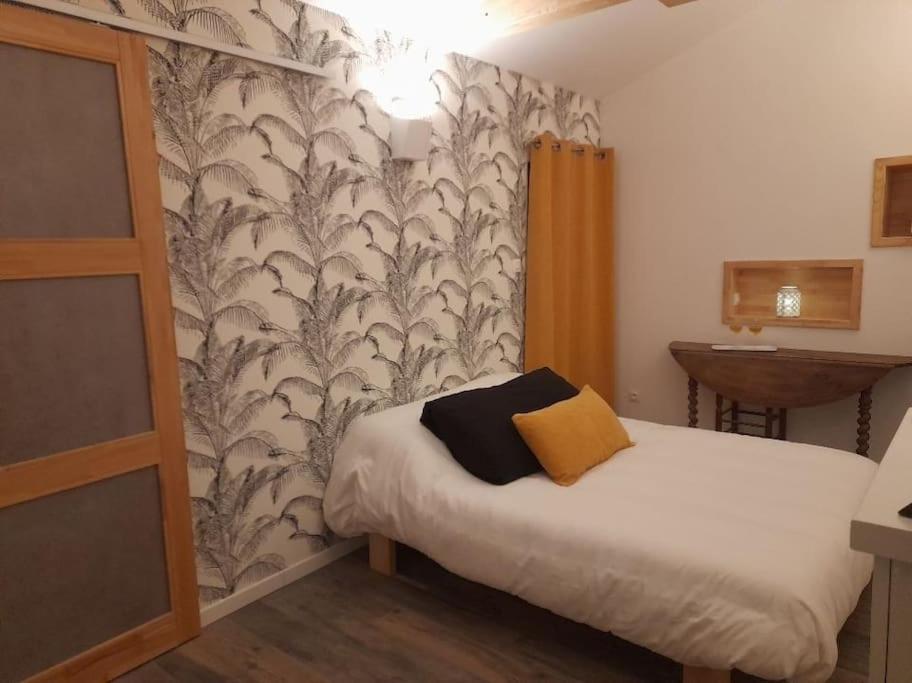Logement avec accès terrasse في Mazières-en-Gâtine: غرفة نوم صغيرة بسرير وورق جدران