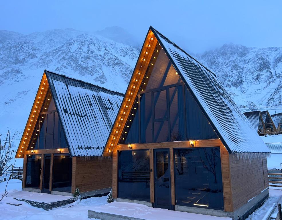 a house in the snow with lights on it at Kazbegi Hills Cottages in Stepantsminda
