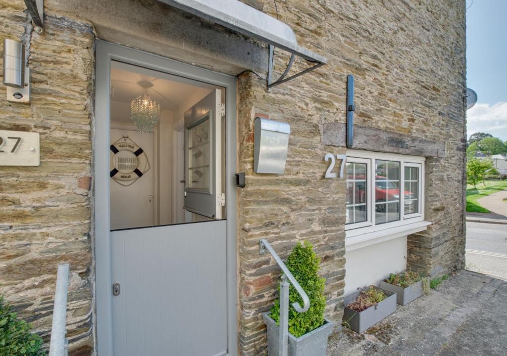 a brick house with a white door and a window at Saltrock Cottage in Kingsbridge