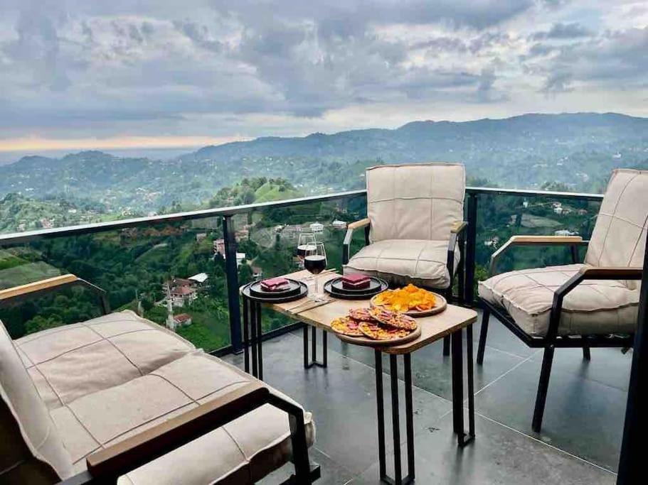 einen Balkon mit zwei Stühlen und einem Tisch mit Essen drauf in der Unterkunft Hills Wooden House in Cayeli