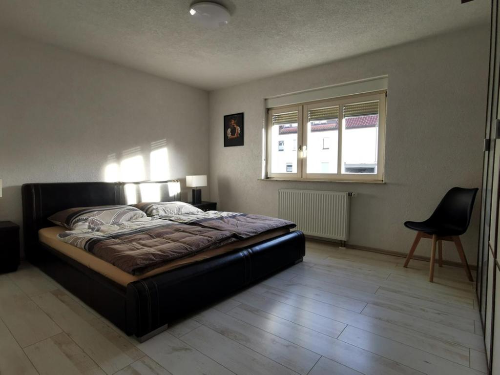 a bedroom with a bed and a chair and a window at 3 Zimmer Ferienwohnung mit eigenem Garten Trossingen in Trossingen