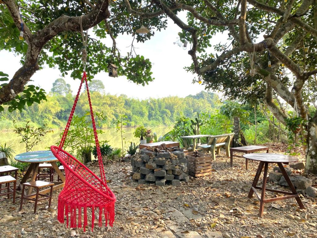 una hamaca colgada de un árbol con una mesa y bancos en Nui Tuong Village Stay, en Tân Phú