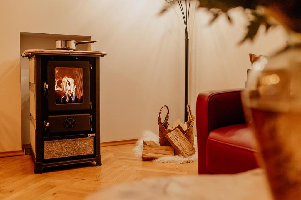 una pequeña estufa en la sala de estar con un sofá rojo en Gemütliche Stadtferienwohnung Leibnitz, en Leibnitz