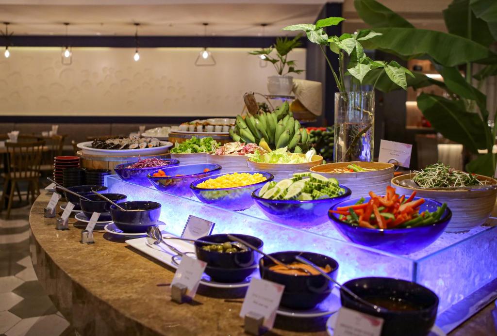 A brightly lit buffet counter presents salads, vegetables, fruit and prepared dishes.