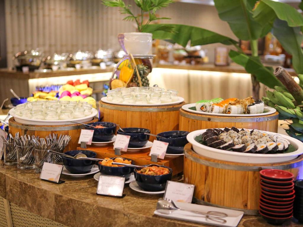 A buffet station displays sushi, chilled items, fruit and condiments in wooden serving barrels.