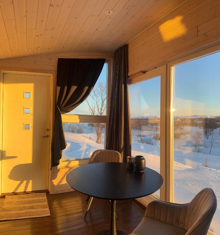 a room with a table and chairs and a large window at Badstue ved elven i Varangerbotn in Varangerbotn