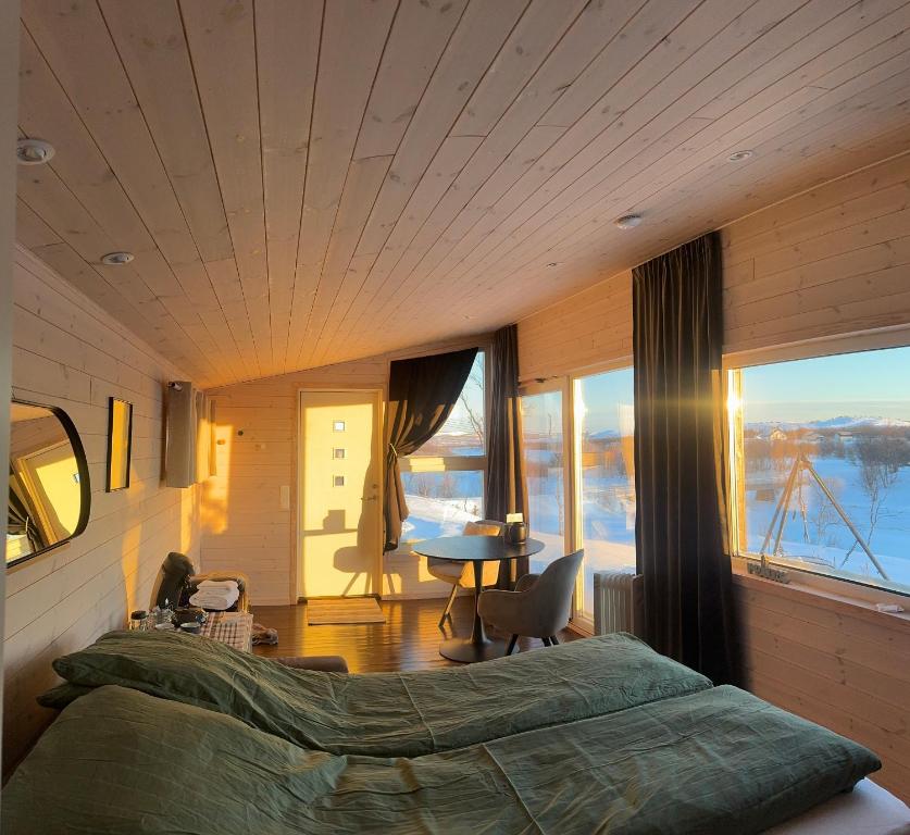 a bedroom with a bed and a table with a view at Nyt sauna under nordlyset, kort avstand fra Varangerbotn in Varangerbotn