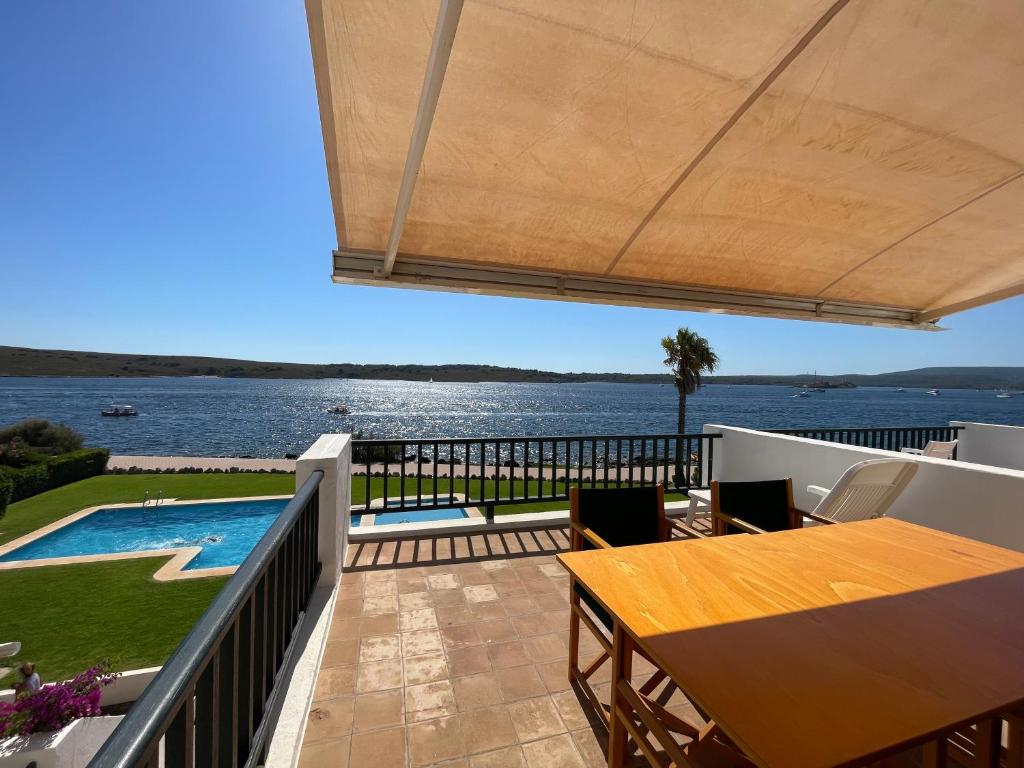 een balkon met een tafel en uitzicht op het water bij ES CASTELL 2 5 by SOM Menorca in Fornells