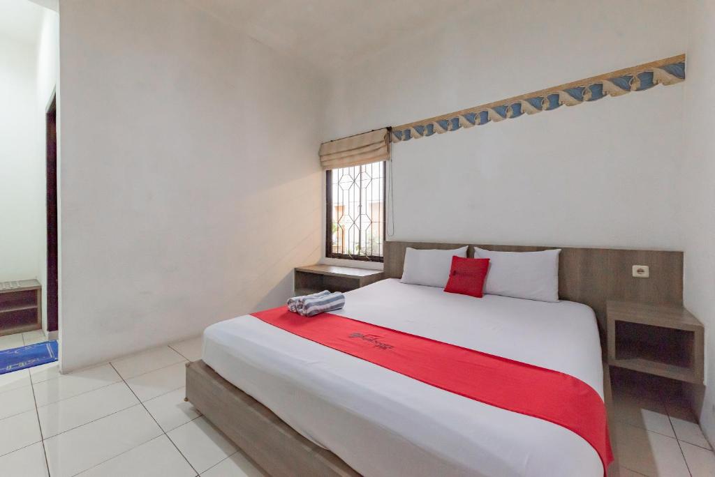 a bedroom with a large bed with a red blanket at RedDoorz near Taman Kota Lapang Merdeka Sukabumi in Sukabumi