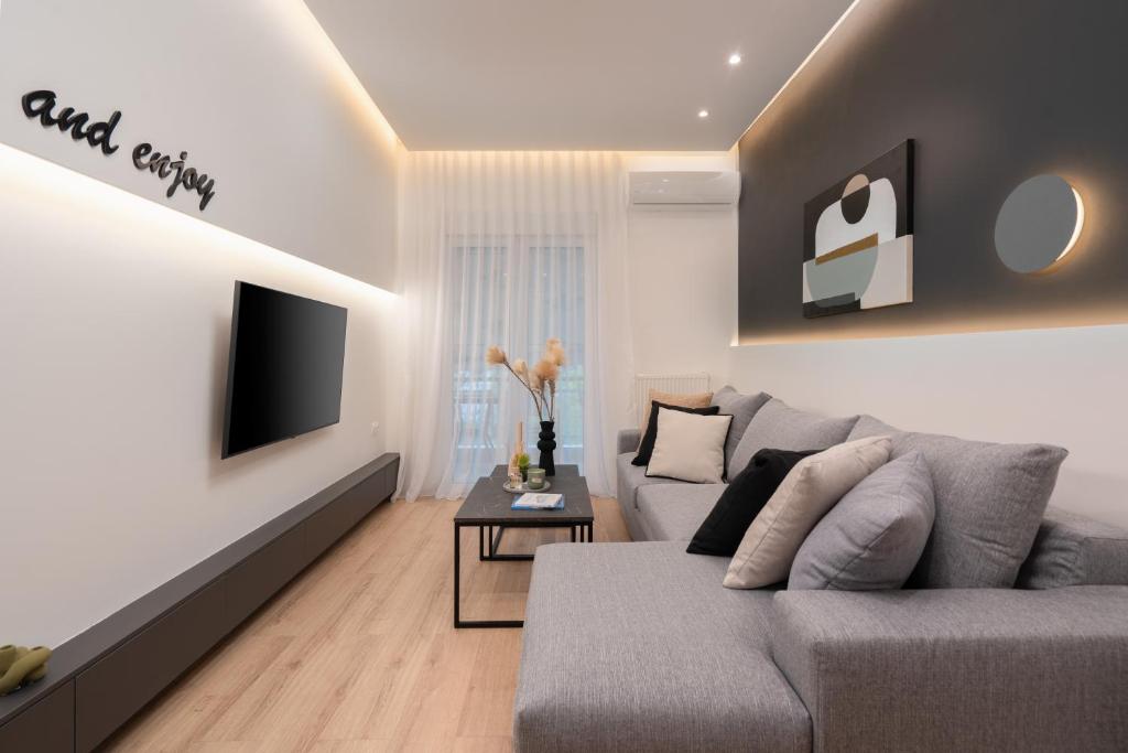 uma sala de estar com um sofá cinzento e uma televisão em Exclusive and Deluxe Apartment in Athens City em Atenas