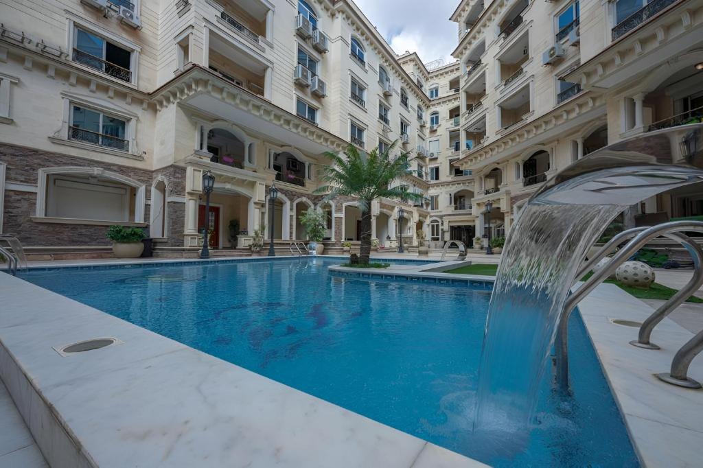 a swimming pool with a fountain in front of a building at Jasmine Pyramids Hotel in Cairo