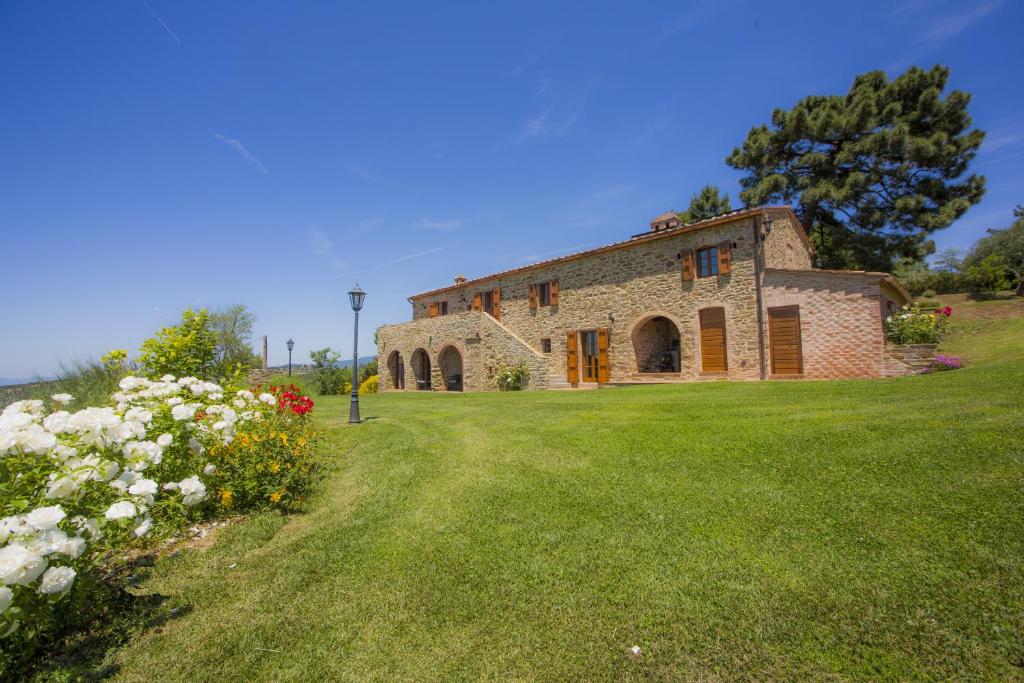 un viejo edificio de piedra en un campo con flores en Tenuta Angelici Winery Casa Contea with pool and panoramic pool Cortona, en Terontola
