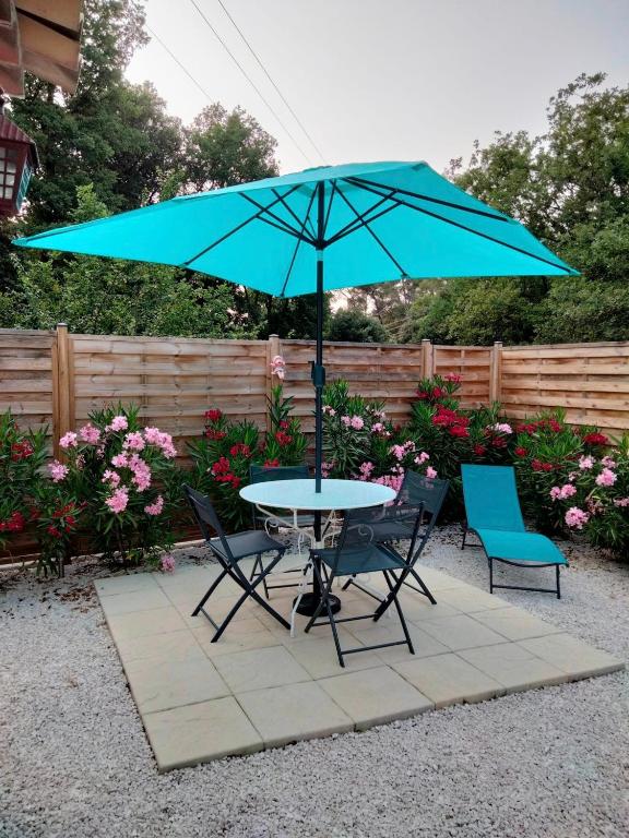 une table et deux chaises avec un parapluie bleu dans l'établissement L'ANNEXE endroit zen et chaleureux. Jacuzzi extérieur, à Brignoles