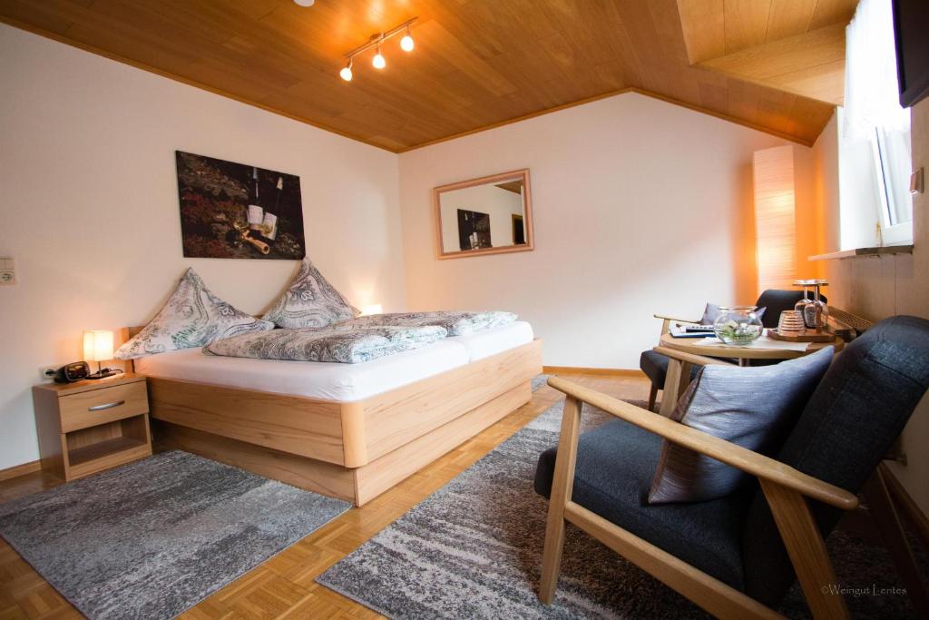 a bedroom with a bed and a table and a chair at Wein- und Gästehaus Lentes in Trittenheim