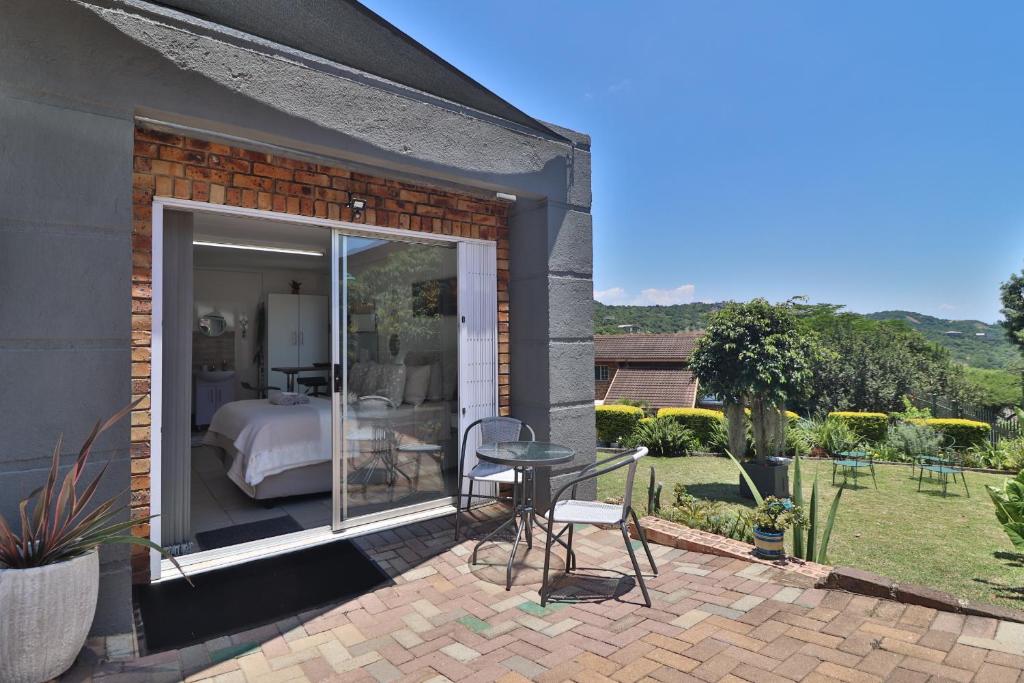 a patio with a bed and a table and chairs at Sleep Haven Self-Catering Accommodation - Nelspruit in Nelspruit