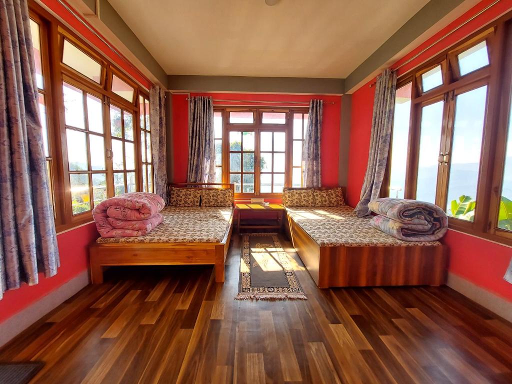 sala de estar con 2 camas y ventanas en Shaguns Homestay by Retrea8stay en Kalimpong