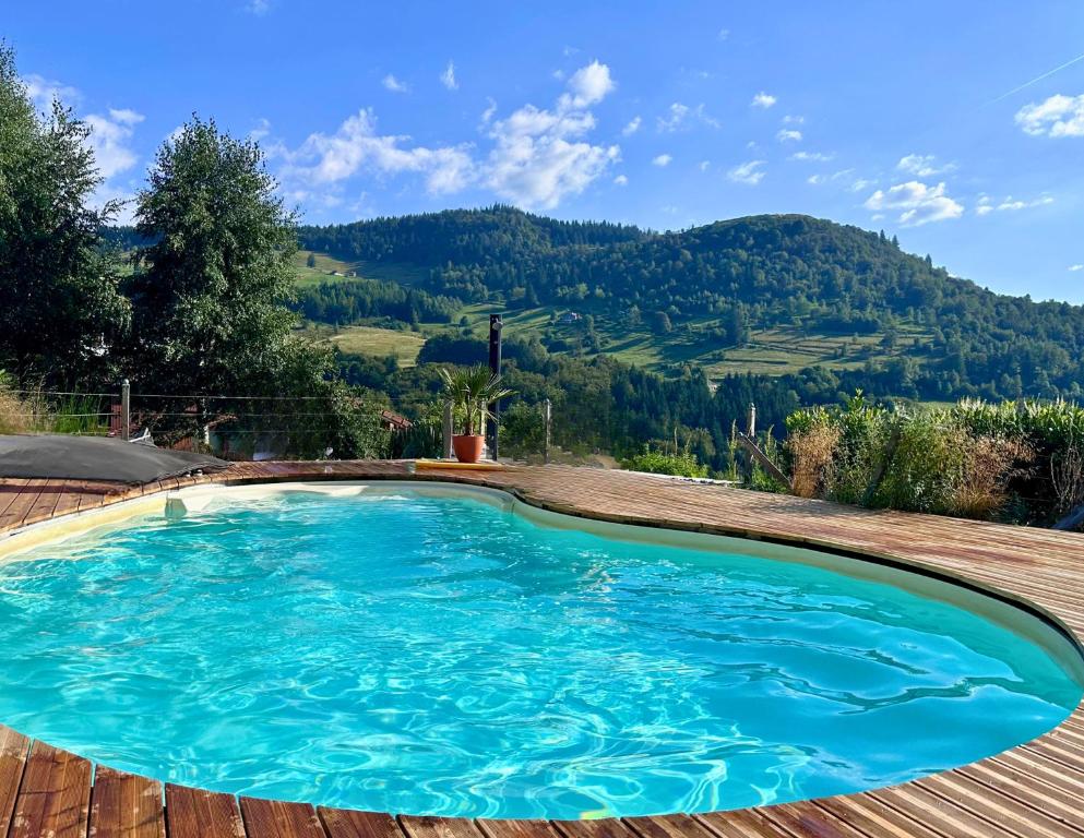 een zwembad op een houten terras met een berg bij Home - Retour aux sources in Le Ménil