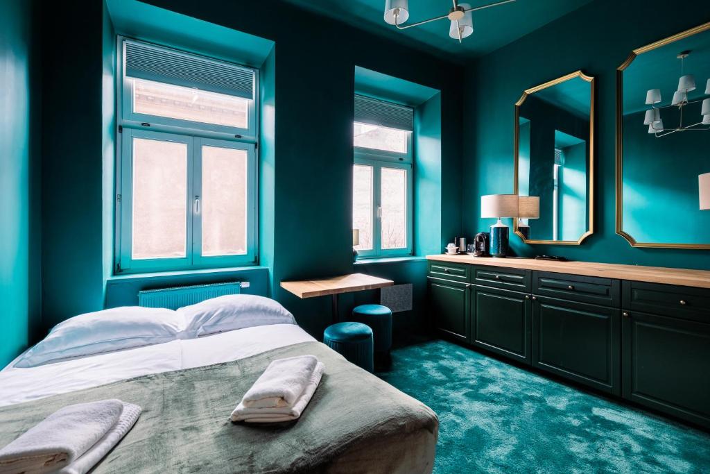 een slaapkamer met blauwe muren en een bed met een spiegel bij Green Gertrudy in Krakau