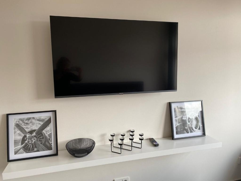 a flat screen tv on a wall with two pictures at Ferienwohnung PIER 2 in Cuxhaven in Cuxhaven