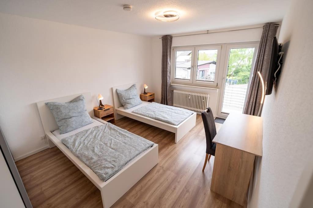 a bedroom with two beds and a desk and a window at Bookandstay24 Münster bei Darmstadt, Frankfurt, Rhein Main Gebiet in Münster