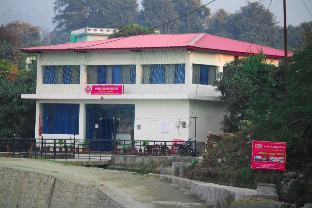 una casa bianca con un cartello rosa davanti di Hotel Glass House a Kāta Patthar