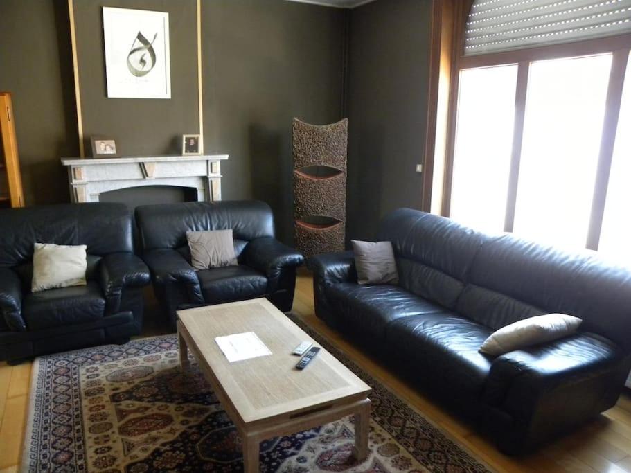Sala de estar con sofá de cuero negro y mesa de centro en Lovely Bourg house 4 pers 2 bedr 2 bath Wifi en Charleroi