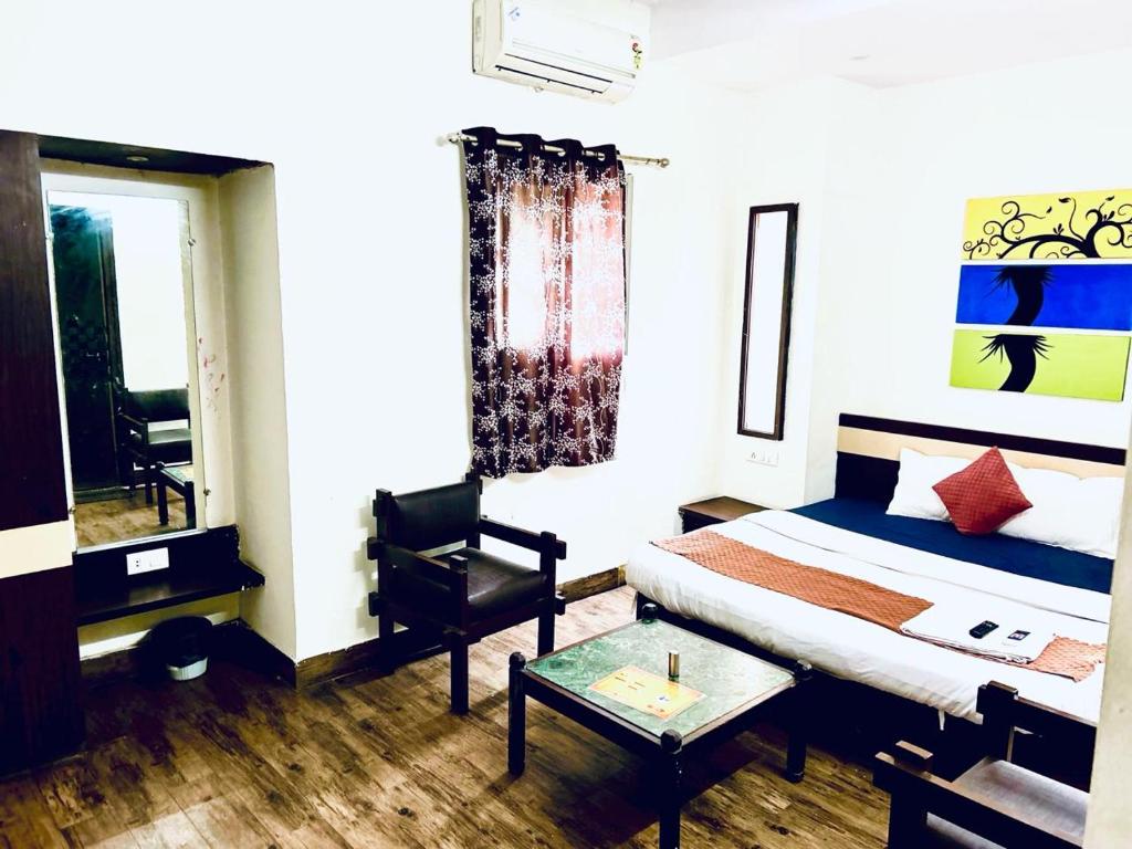 a bedroom with a bed and a chair and a table at HOTEL SUNSHINE in Nagpur