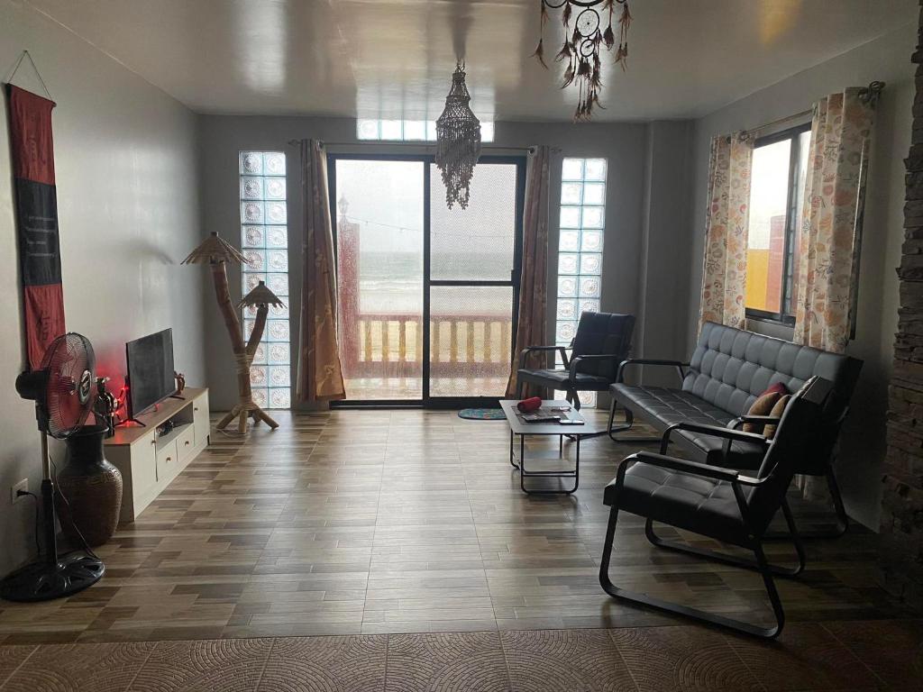 uma sala de estar com um sofá, cadeiras e uma mesa em Koa's Beach House em Tangalan