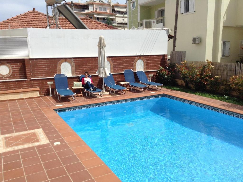 a person sitting in chairs next to a swimming pool at VERA’S APARTMENT in Markopoulo