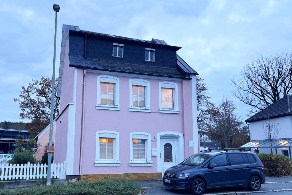 une camionnette garée devant une maison rose dans l'établissement Ferienhaus Selbitz, à Selbitz