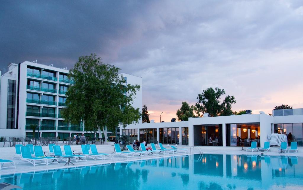 una piscina con sedie blu e un edificio di Hotel Turquoise All Inclusive a Venus