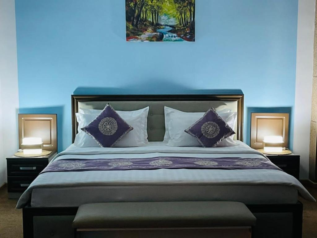 1 dormitorio con 1 cama grande con almohadas moradas en Hotel Shumon en Dusambé