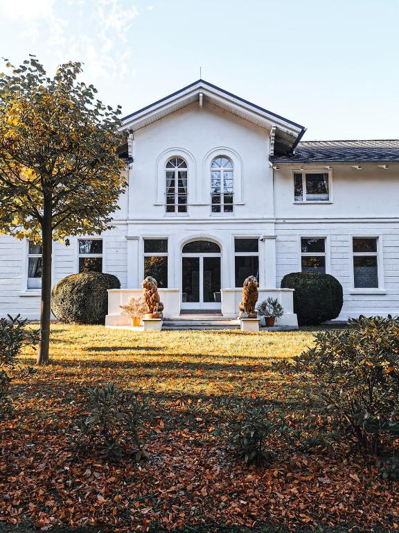 a white house with two statues in front of it at Meeressterne Hotel Weißes Schloß in Heringsdorf