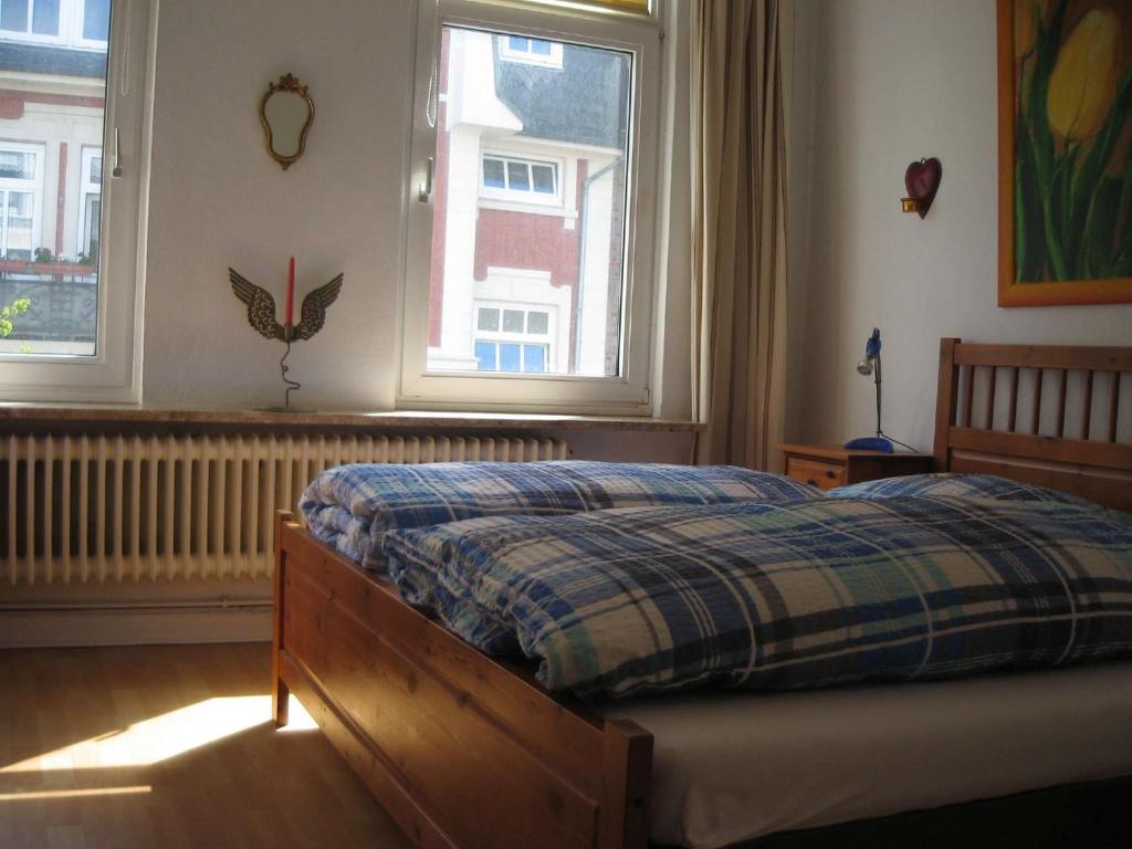 a bedroom with a bed and two windows at Haus Sonnensegler - Ferienwohnung in Cuxhaven