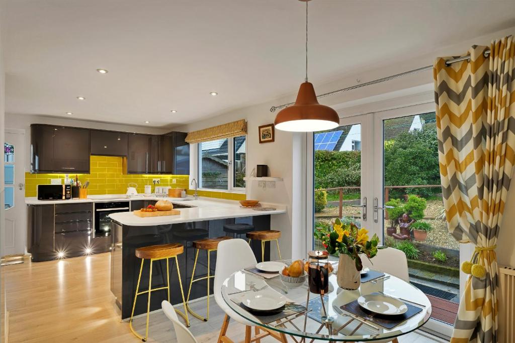 a kitchen with a table and chairs and a kitchen with yellow at Finest Retreats - Beyond The Blue in Porthleven